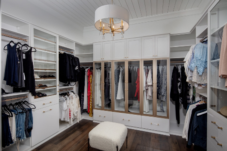 interior of a large walk in closet with cabinetry and shelving with organized clothes