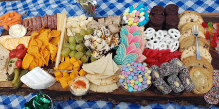 large charcuterie board with various things on it on a checkered blue and white tablecloth