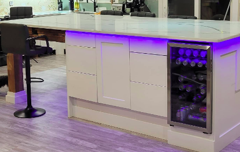Kitchen island with purple under lighting and beer fridge on the right