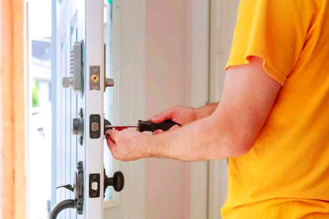 Man taking a screwdriver to a lock from the inside wearing a yellow shirt