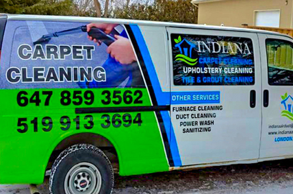 Work van with blue and green company details on the side parked outside