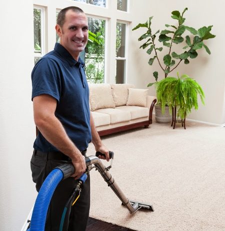 Man smiling at camera holding a carpet cleaner