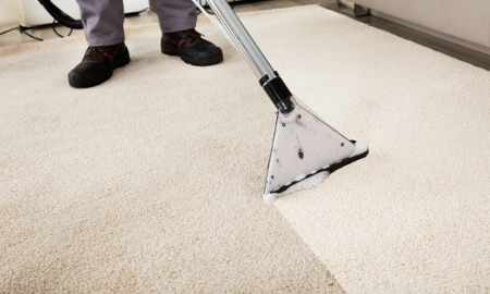 Man using carpet cleaner on a white carpet with dirty part showing