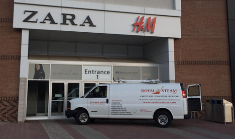 white work van parked outside a mall entrance with back door open