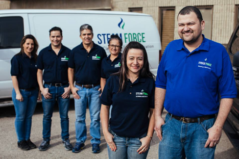 work team posed in front of work truck outside with man and woman closer to camera