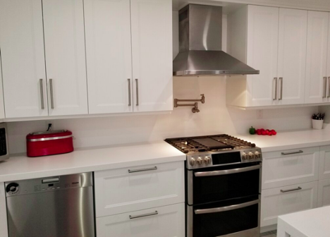 view of stove with white cupboards and white countertops with red accents in the kitchen