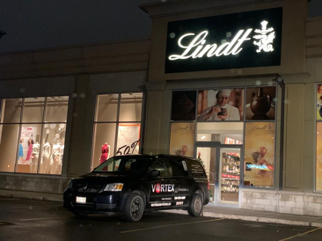 black work van rear parked in front of a chocolate store at night