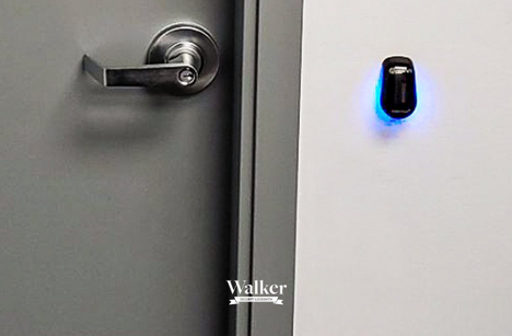 Exterior key fob system sitting to the right of a door handle on the wall with a blue light