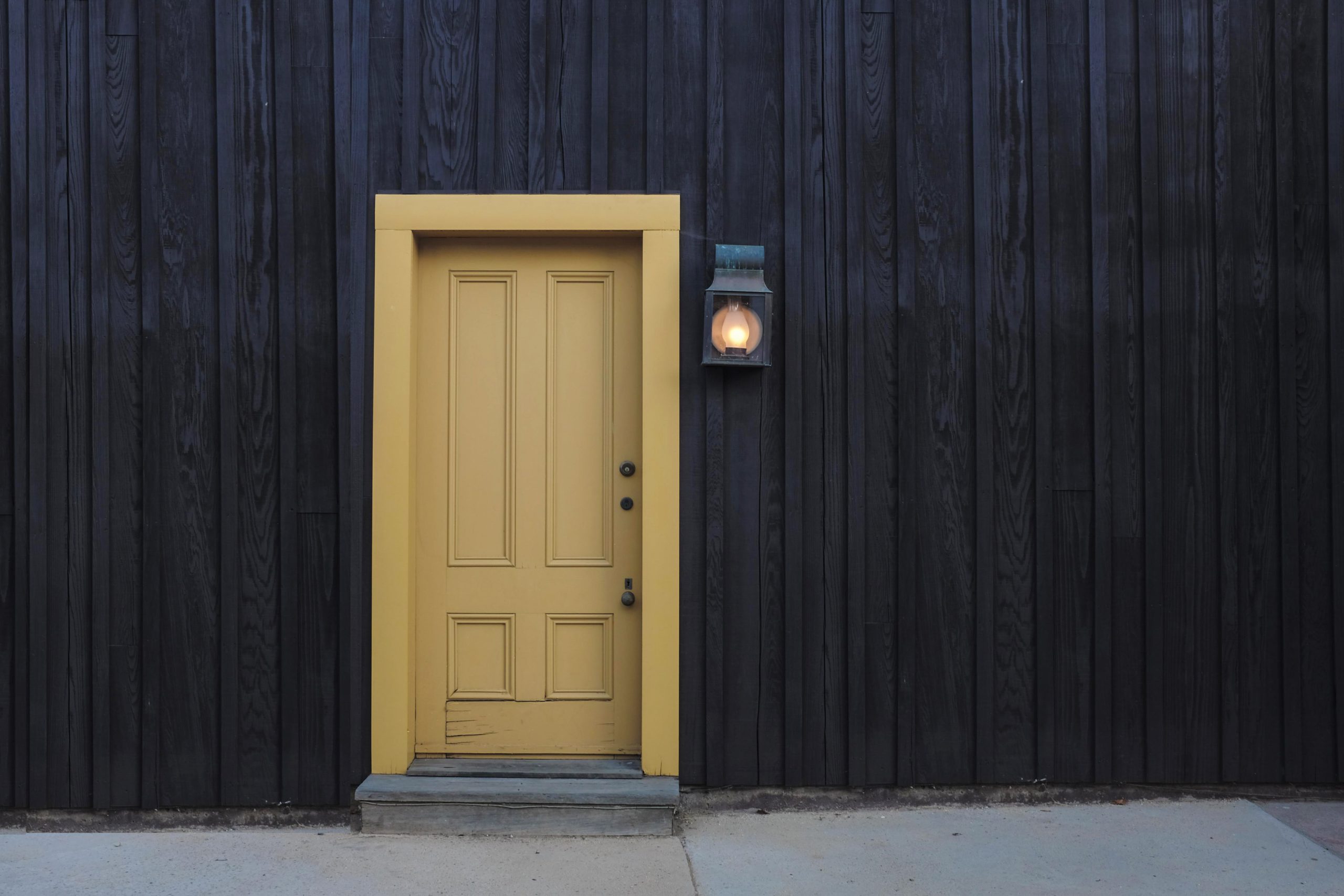 yellow door against a black wall with light outside