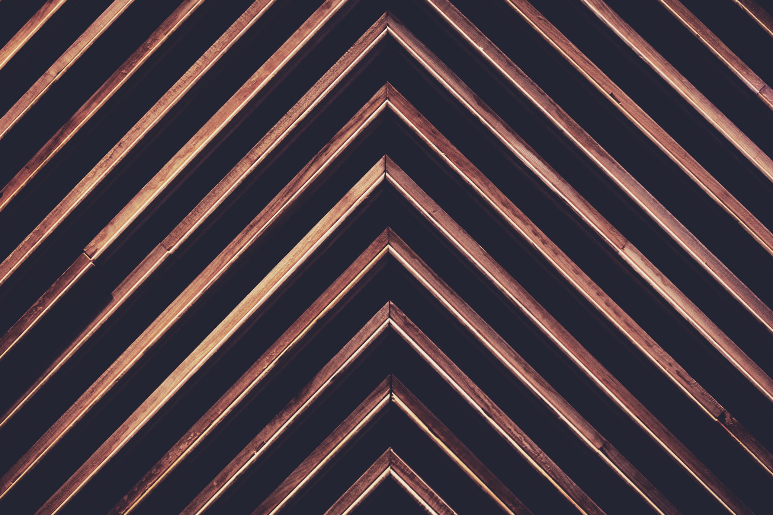 pieces of darker wood angled up against a black wall to make an arrow