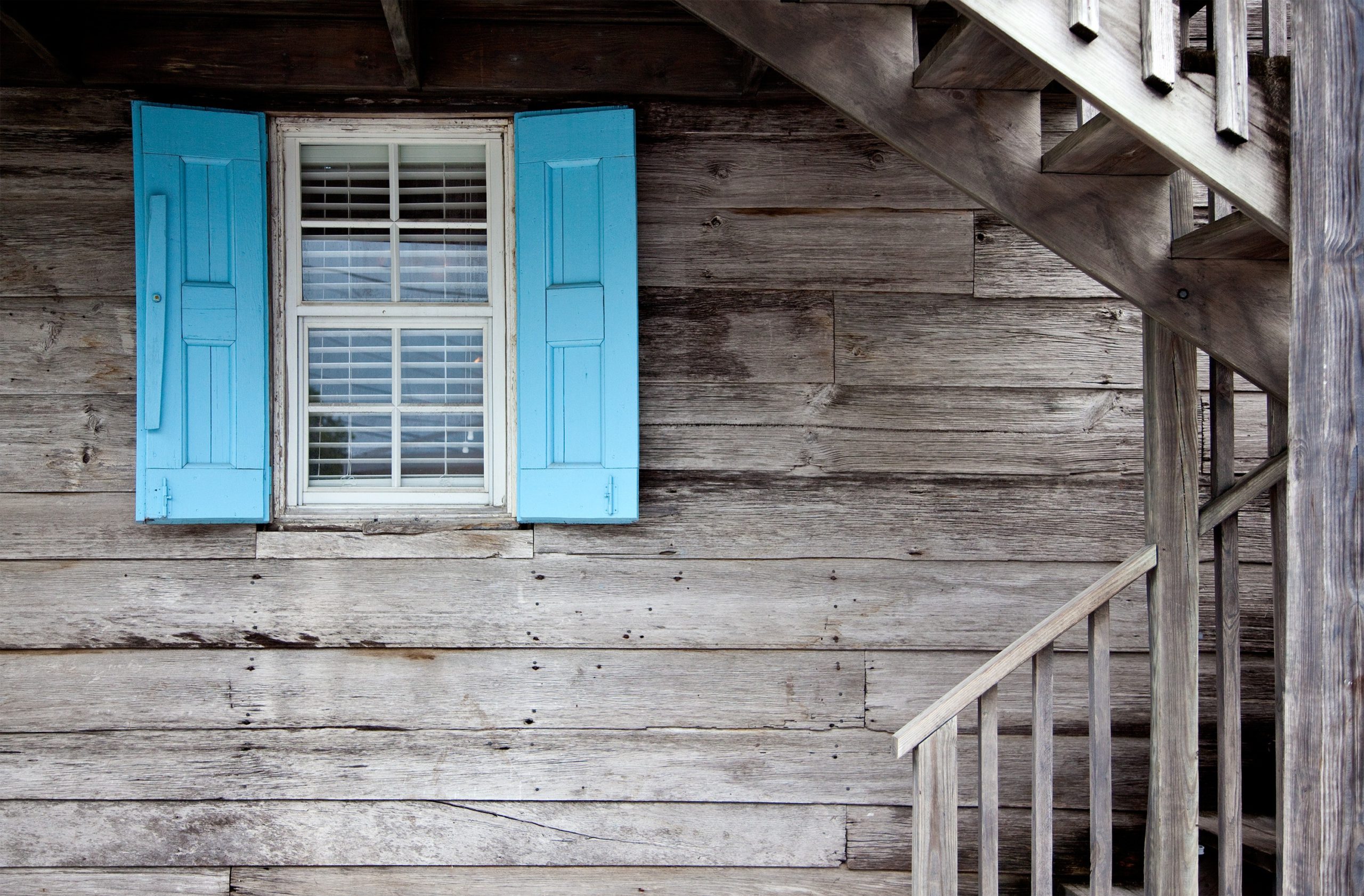 Older home with old window featuring bright blue shutters