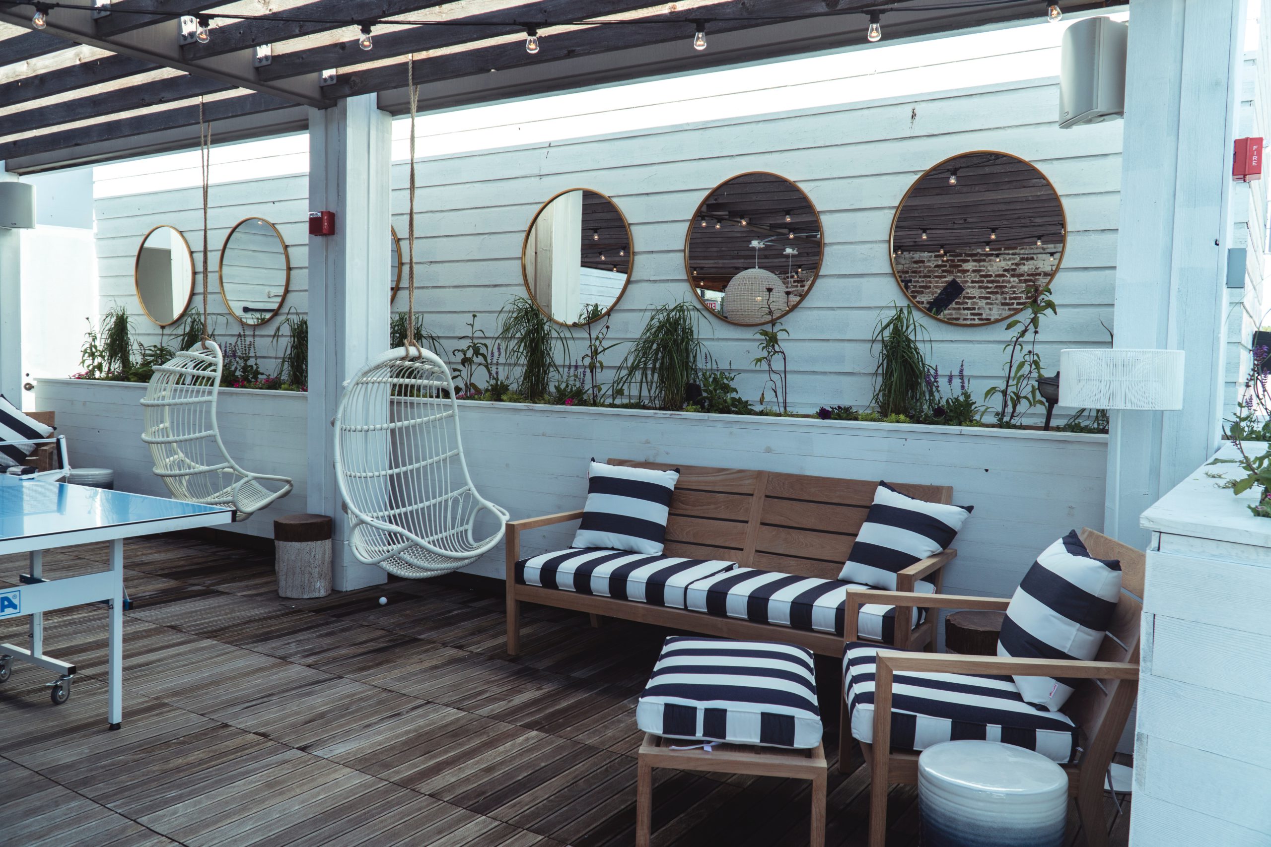 Outdoor space with striped cushions and egg swinging chairs set up in corner