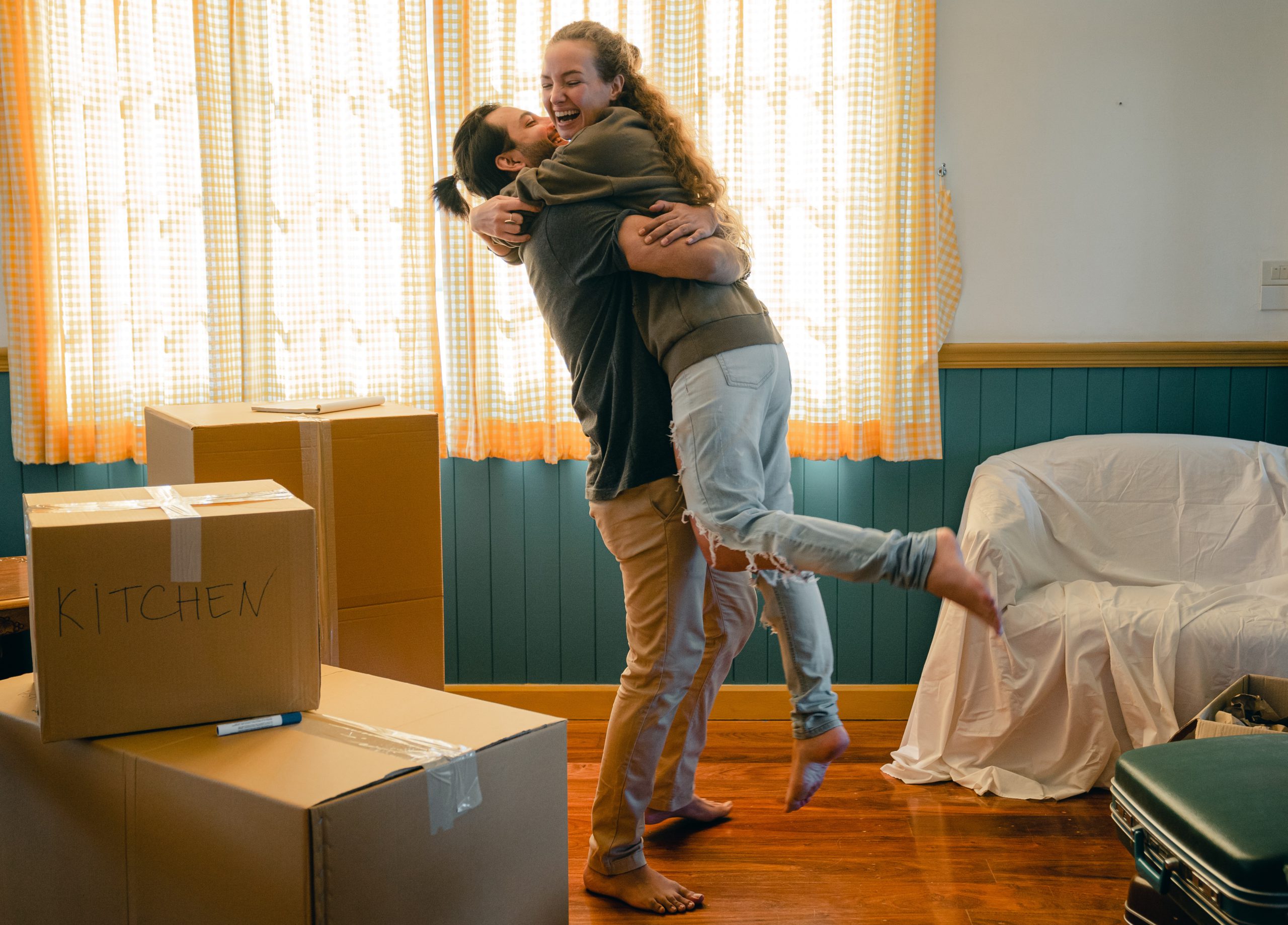 Couple hugging in their new home with moving boxes surrounding them