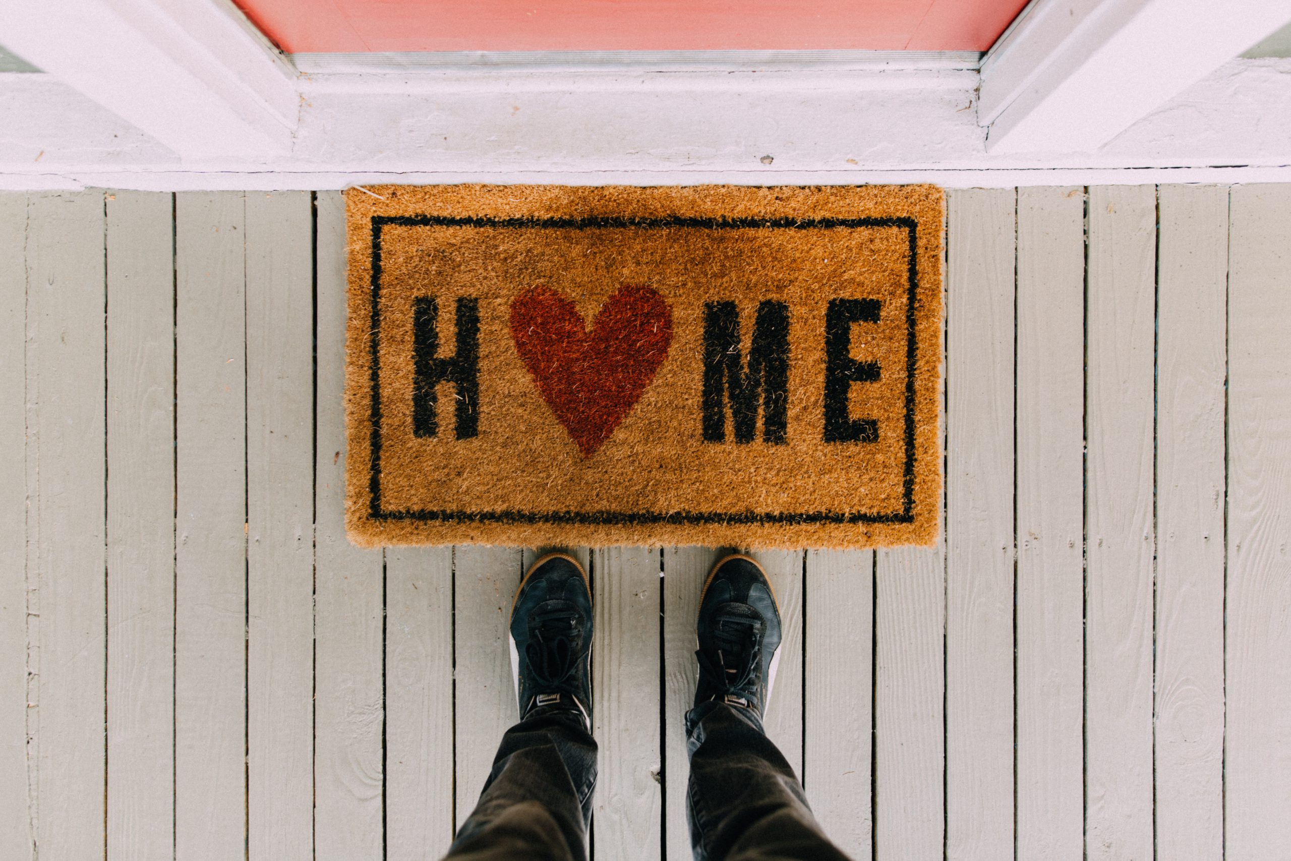 Floor mat with home written on it but a heart instead of an o with feet visible