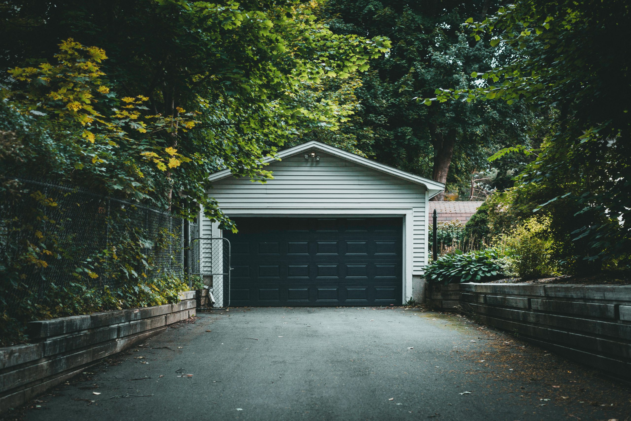 Outdoor garage at the end of a driveway with many trees