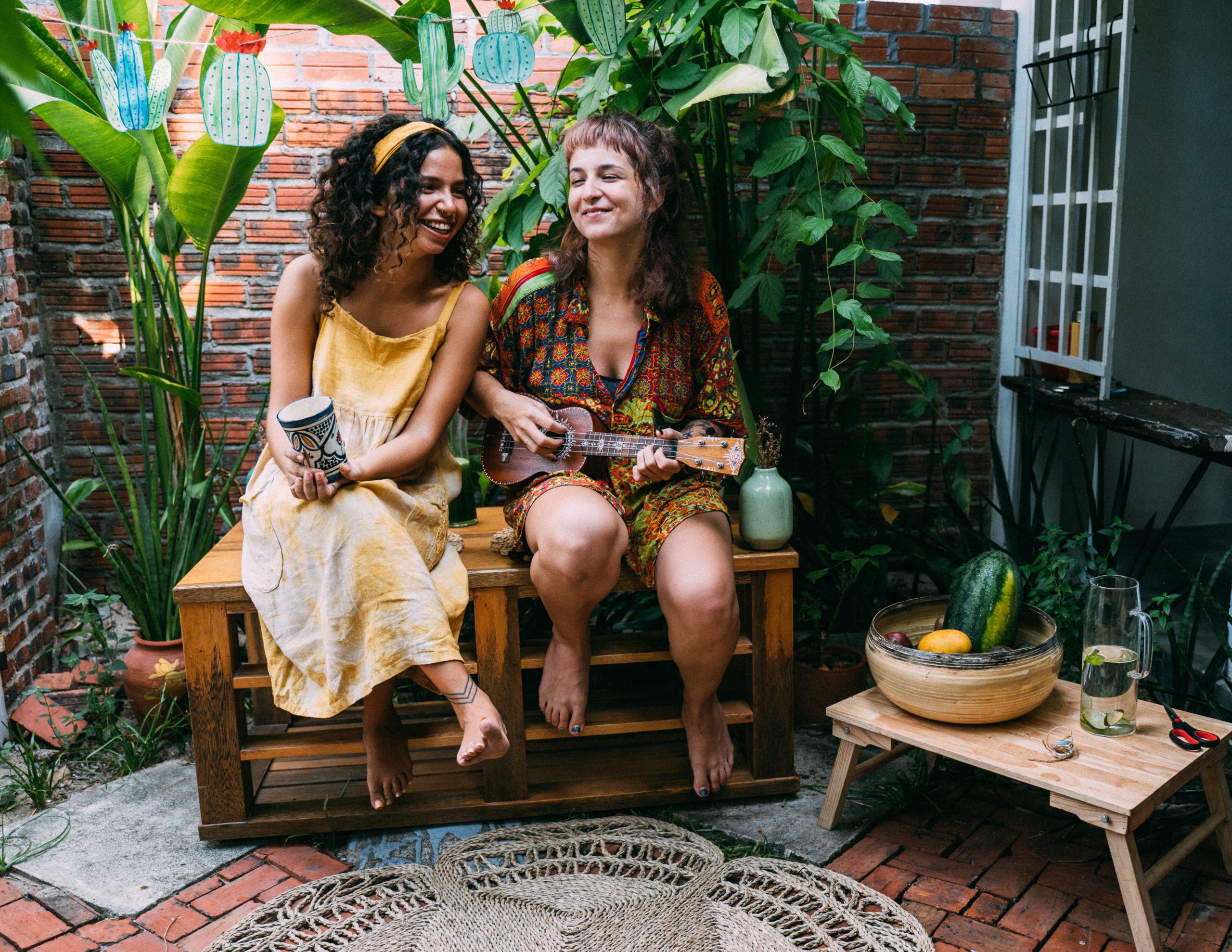 Two ladies sitting on a back porch with various plants surrounding them