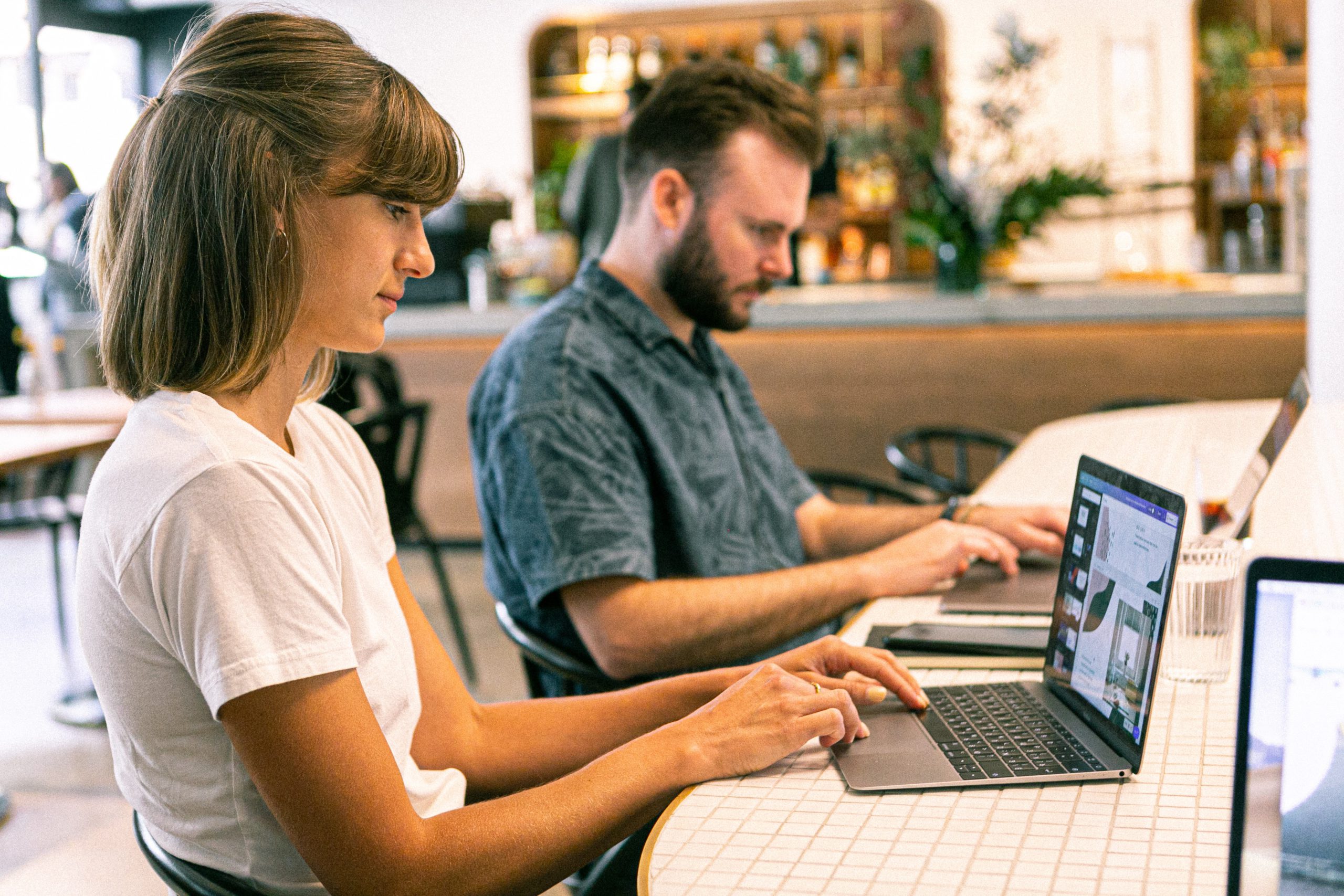 Man and woman on laptops at an office desk looking at their screens