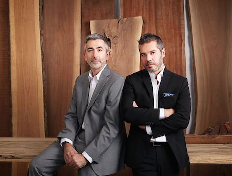 two men in suits in front of live edge wooden slabs