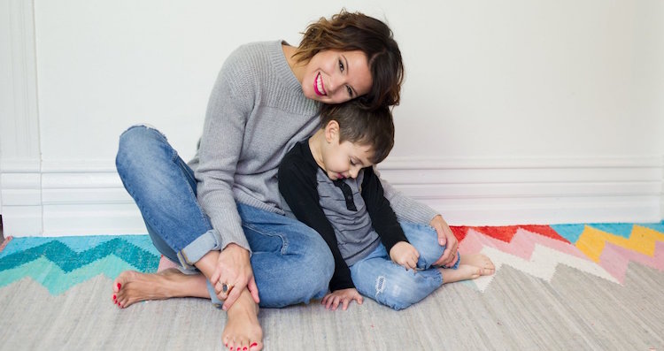 woman and son hugging sitting on carpeted floor in front of white wall