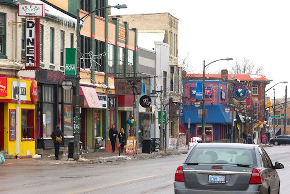 view of downtown core storefronts with car driving down the street