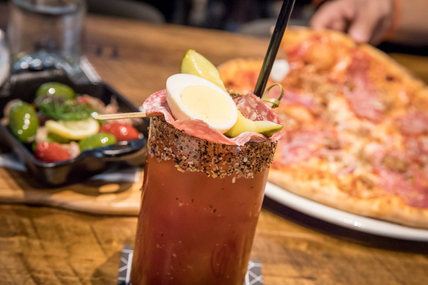 caesar drink with garnish, pizza and other side dish side view 