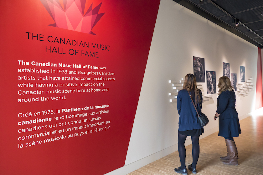 women standing in front of display at canadian music hall of fame looking at exposition