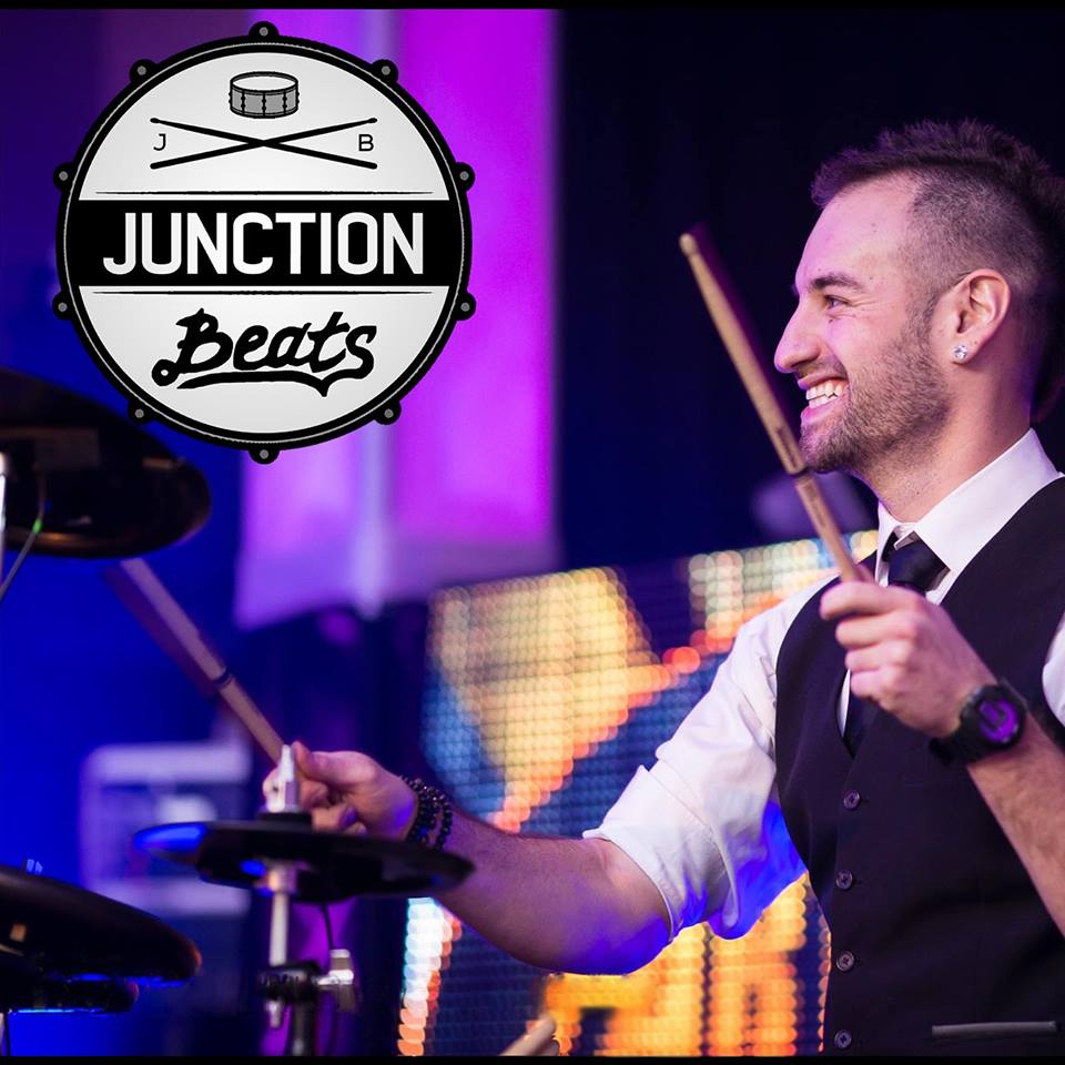 junction beats advertisement with man playing drums wearing collared shirt and vest looking happy