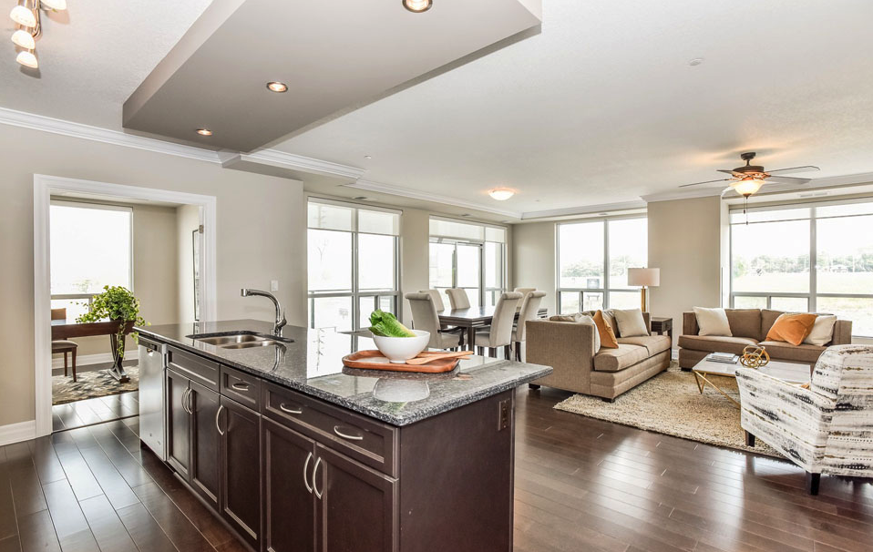interior of large condo with light accents, large windows and open concept featuring island