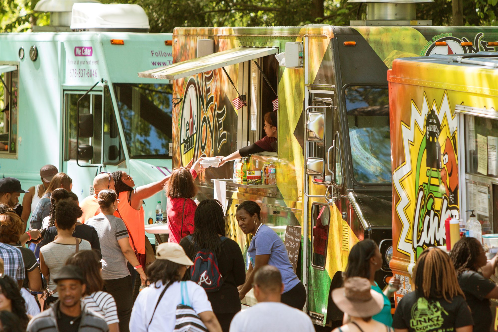 food trucks with many patrons surrounding on a bright day with bright colours
