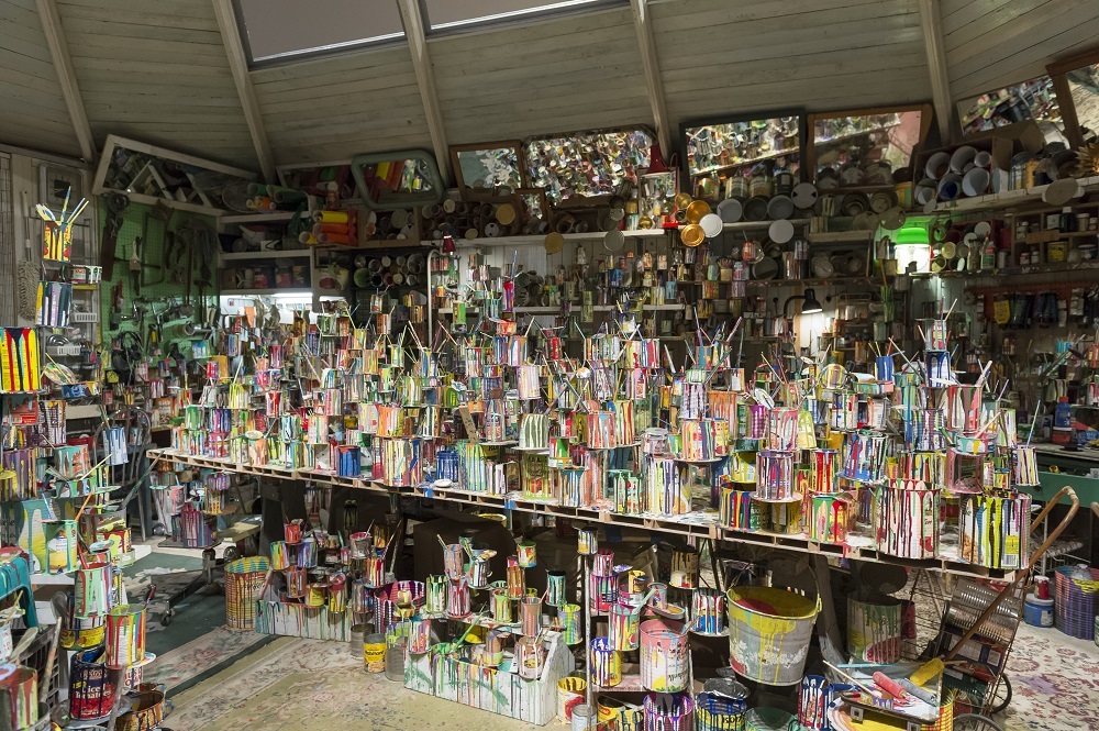 paint bucket art with many colours on shelf in an enclosed shed