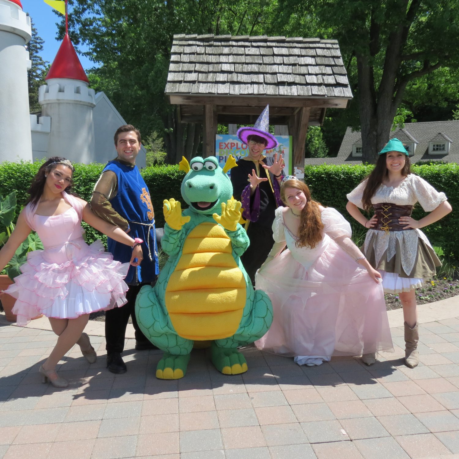 Park staff in costumes in front of castle entrance and sign