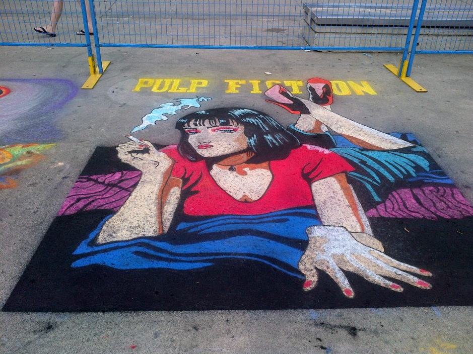 close up of chalk drawing on pavement of woman from pulp fiction behind fence in full colour