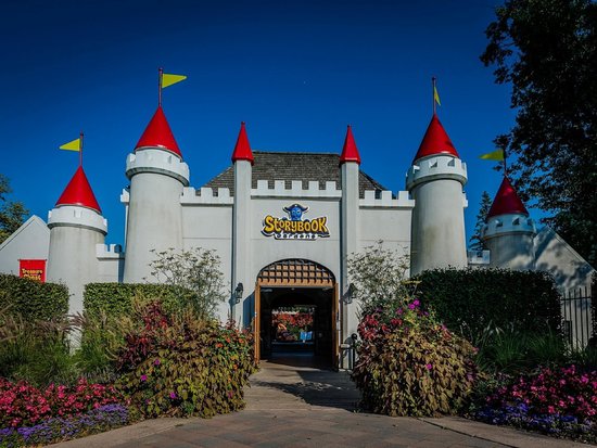 outdoor castle entrance to kids theme park with red roof and yellow flags and garden out front