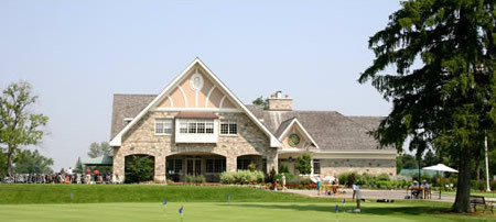 exterior of golf course clubhouse with large arch and putting green out front