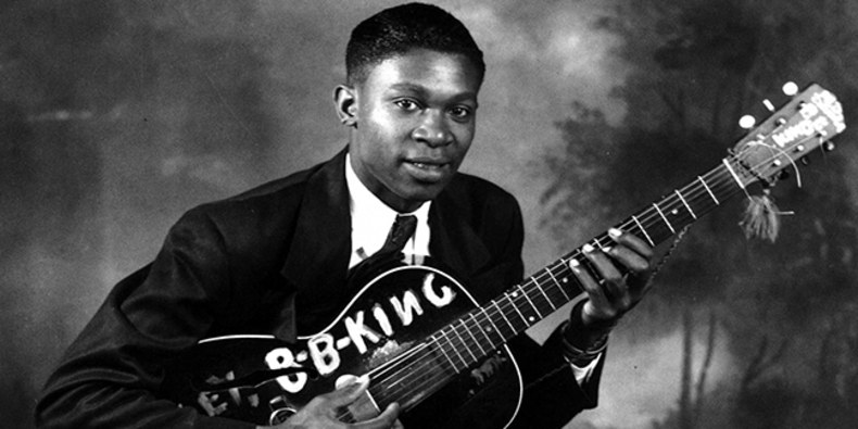 historic black and white photo of man posing with a guitar