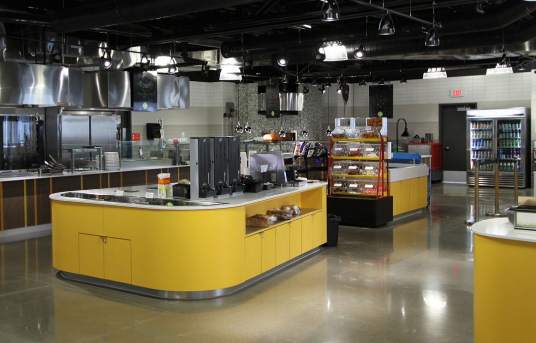interior of cafeteria with yellow counters, no patrons, and stocked shelves ready for service