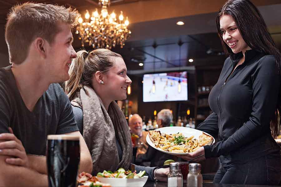 Golf Club waitress serving dinner to a couple in sports bar atmosphere