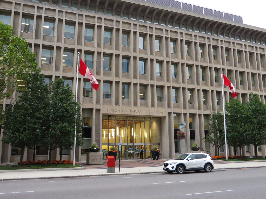 front view of large building with car in front and two canadian flags flying