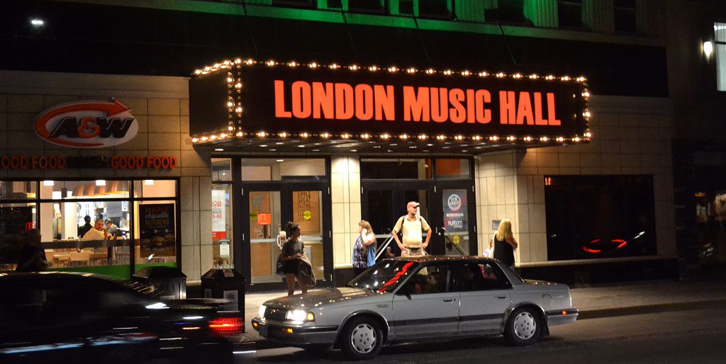 front view of hall with red sign and show lights surrounding with car in front