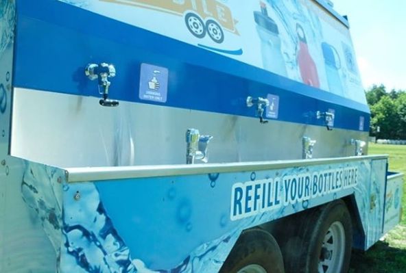 close up of blue water truck with three fountains sticking out the side and a sink on the bottom third of truck