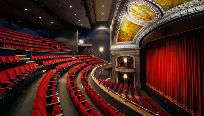 inside seating upper level of performance theatre with red seats and red curtain