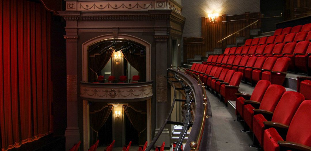 interior of theatre with red seating and balcony views