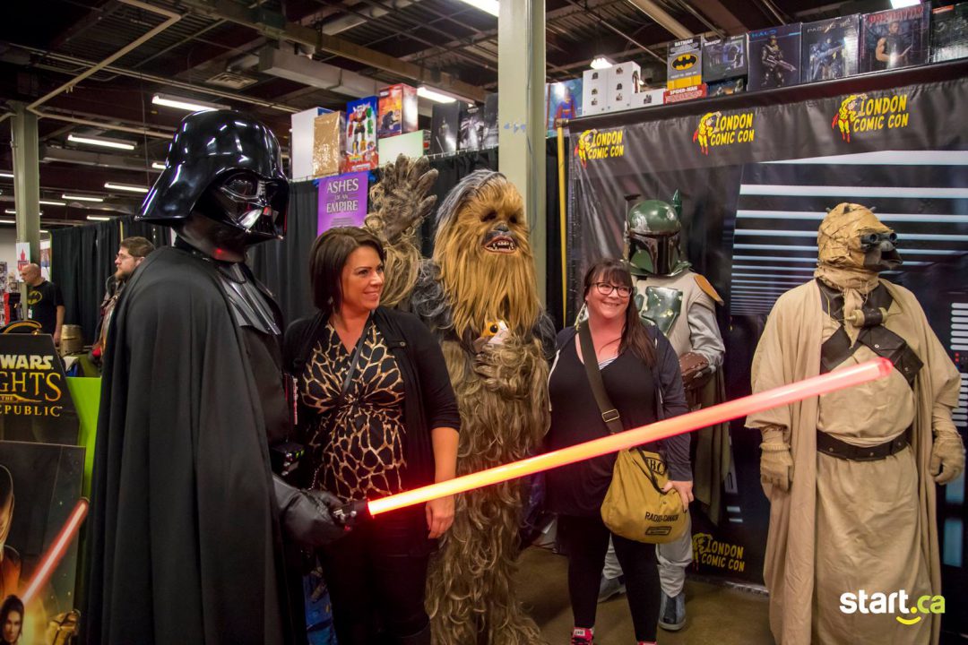 two ladies posing with people in star wars costumes smiling towards camera to the right inside store