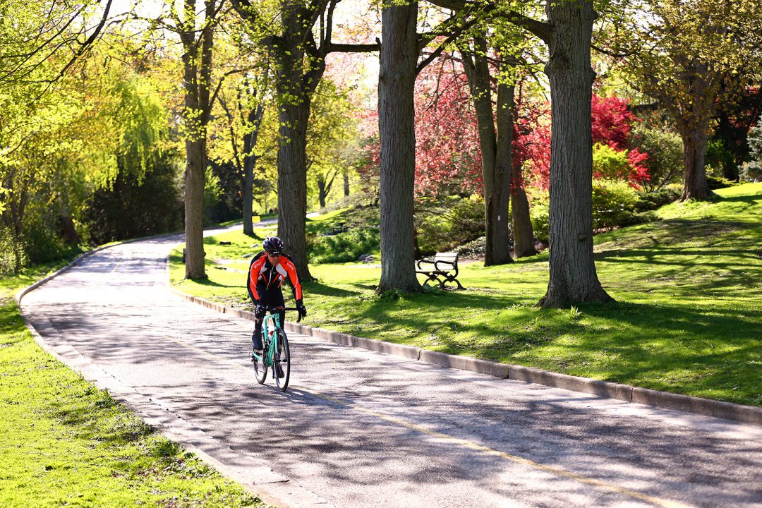 cyclist biking through bike bath in park wearing red jacket on a sunny day