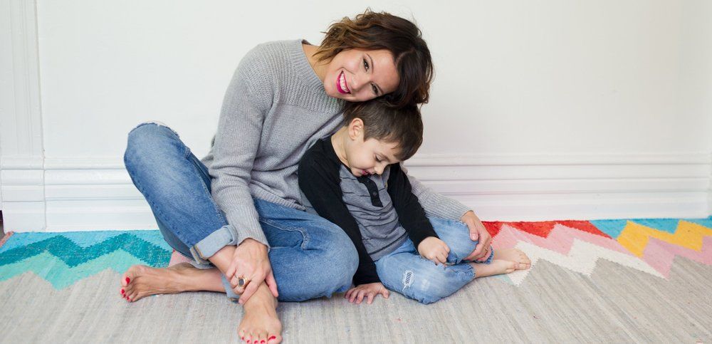 woman and son sitting on floor cuddling on colourful carpet
