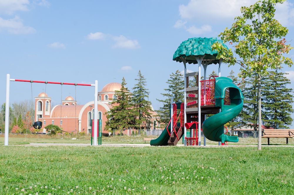 Green and red playground in the summer in front of large church