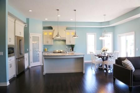 interior of home with light blue walls looking towards kitchen and dining room with white accents