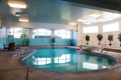 indoor pool with large windows and seating area surrounded by plants
