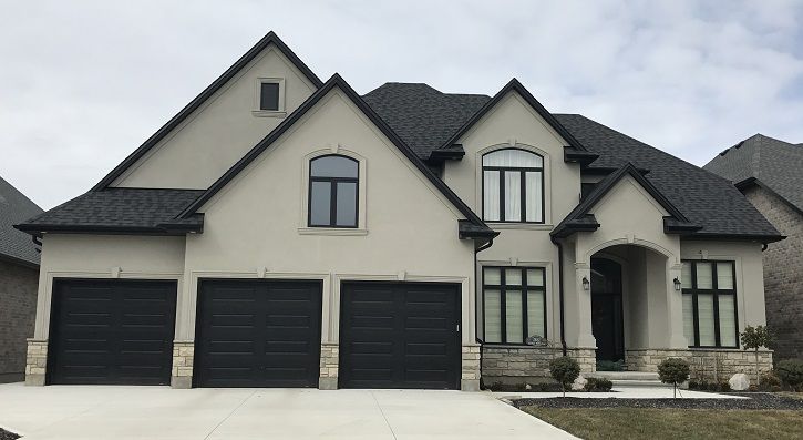 exterior of three car garage grey stucko house with black finishes