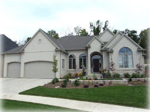 exterior of grey home with landscaping and three car garage